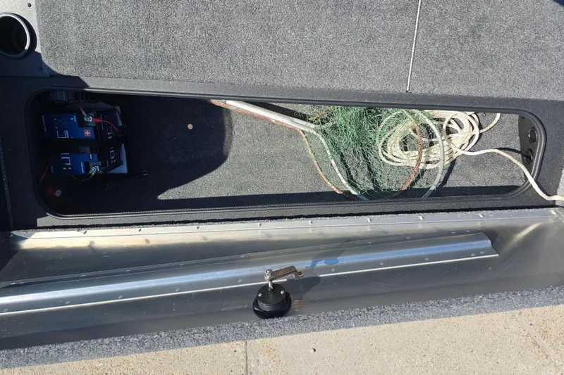 Slide: The Image of 2024 Tracker Pro Team 190 TX storage compartment with battery and fishing net. - 15