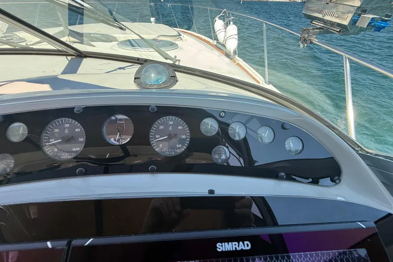 Slide: The Image of 1997 Maxum 4100 SCR yacht dashboard with gauges and Simrad display on open water. - 31