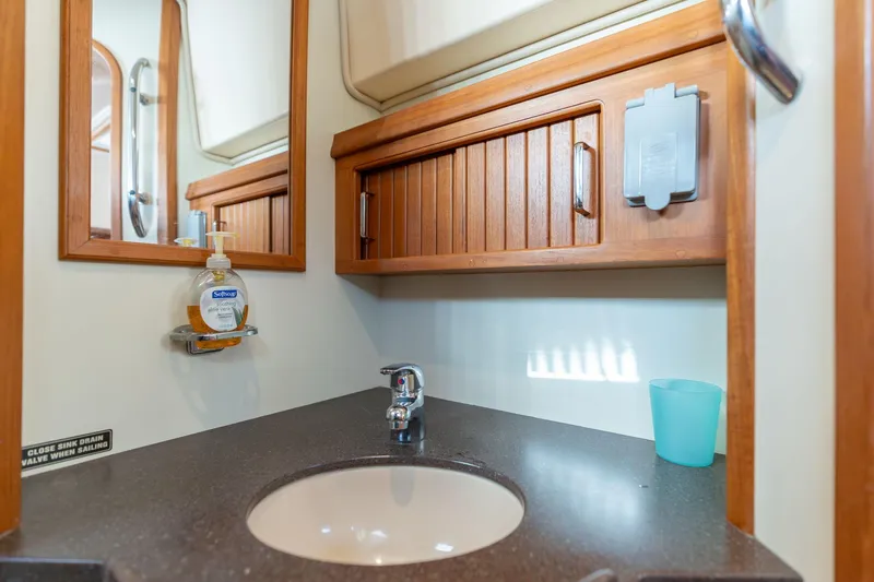 Slide: The Image of 2008 Island Packet 465 yacht bathroom with sink, mirror, and wooden cabinetry. - 21