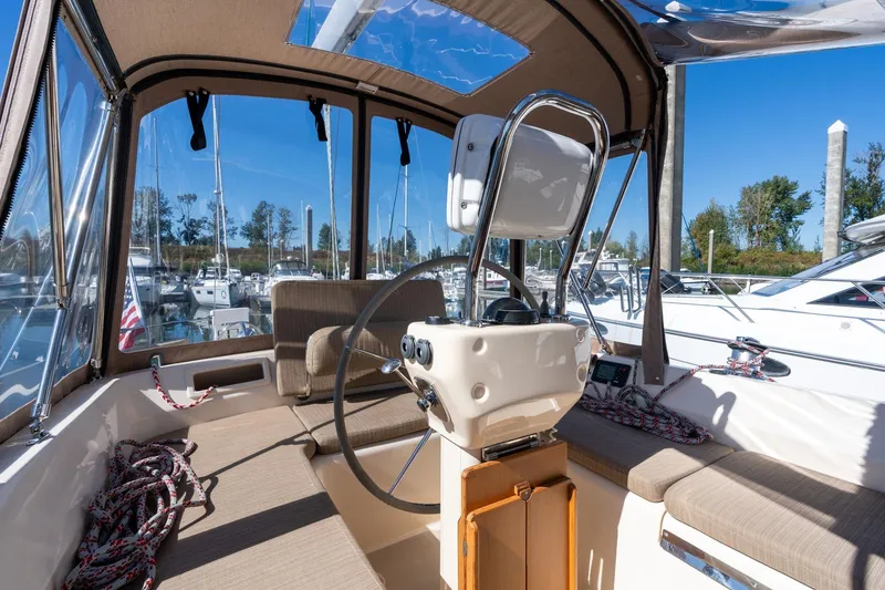 Slide: The Image of 2008 Island Packet 465 yacht cockpit with steering wheel, seating, and marina view. - 40