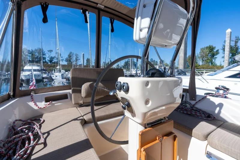 Slide: The Image of 2008 Island Packet 465 yacht cockpit with steering wheel, seating, and marina view. - 43