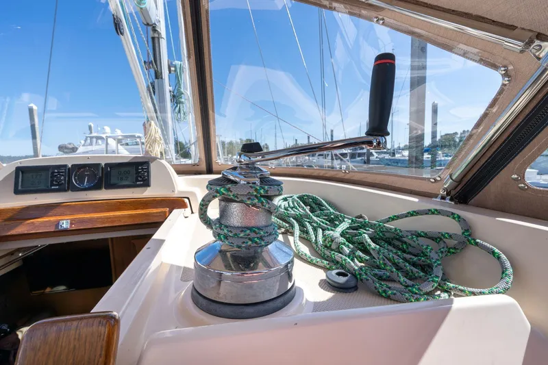Slide: The Image of 2008 Island Packet 465 sailboat cockpit with winch and ropes, marina view. - 52