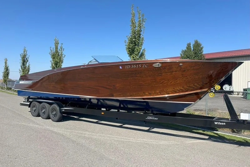 The Image of 2023 StanCraft 380 Rivelle boat on trailer, showcasing sleek wooden design under clear blue sky. - 1