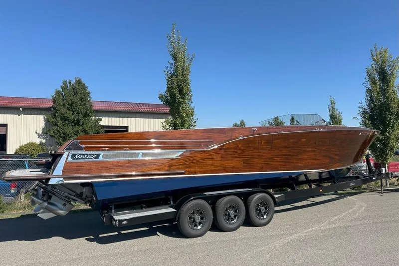 Slide: The Image of 2023 StanCraft 380 Rivelle boat on trailer, showcasing sleek wooden design under clear blue sky. - 3