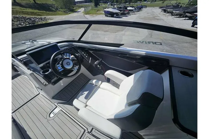 Slide: The Image of 2023 Yamaha Boats 252SD cockpit with modern steering and seating, parked outdoors. - 12