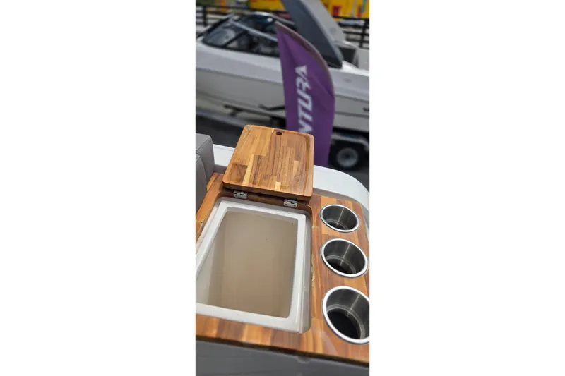 Slide: The Image of 2025 Ventura Daycruiser boat interior with wooden countertop and built-in cup holders. - 12