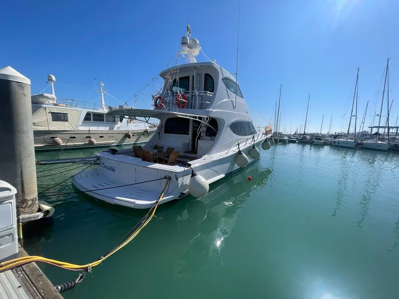Slide: The Image of 2013 Hatteras 63 GT Enclosed Bridge yacht docked in a marina under clear blue sky. - 0