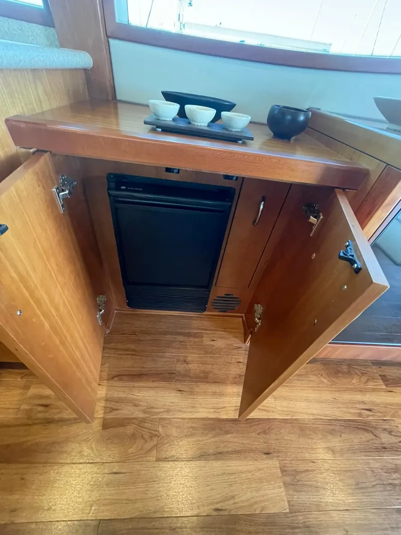 Slide: The Image of 2013 Hatteras GT63 yacht interior with open wooden cabinet and small refrigerator. - 43