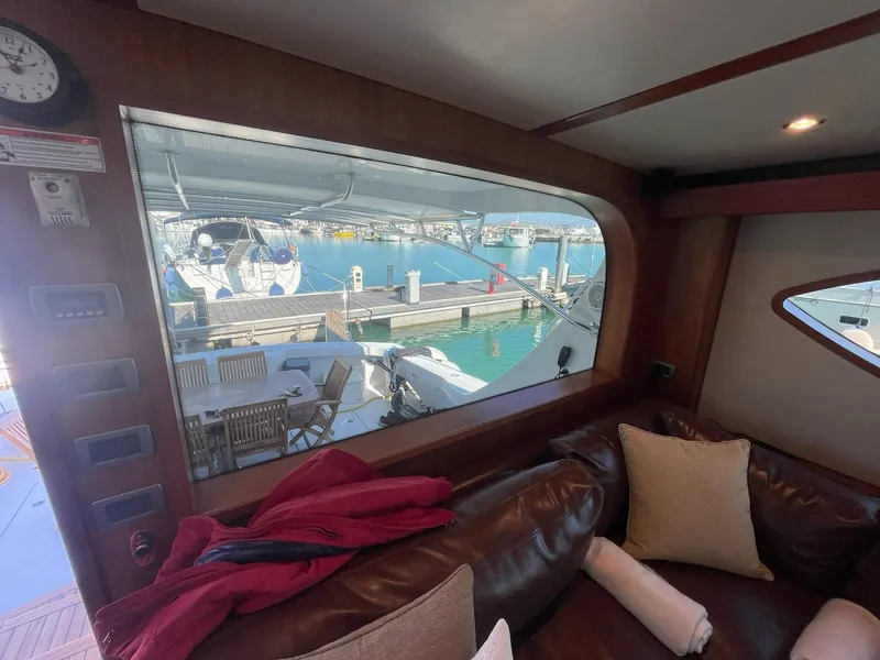 Slide: The Image of Interior view of a 2013 Hatteras GT63 yacht, showcasing marina through large window. - 49