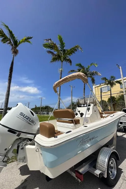 Slide: The Image of 2025 Pioneer 180 Islander boat with Suzuki engine, parked under palm trees. - 1
