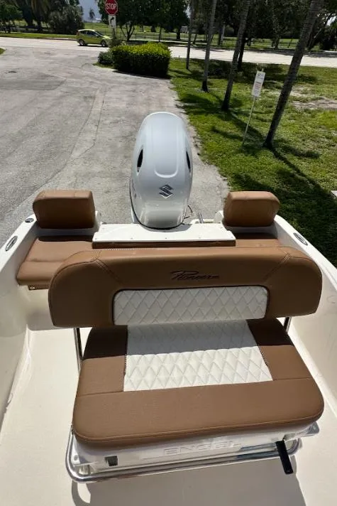 Slide: The Image of 2025 Pioneer 180 Islander boat with brown and white seating, parked outdoors. - 4
