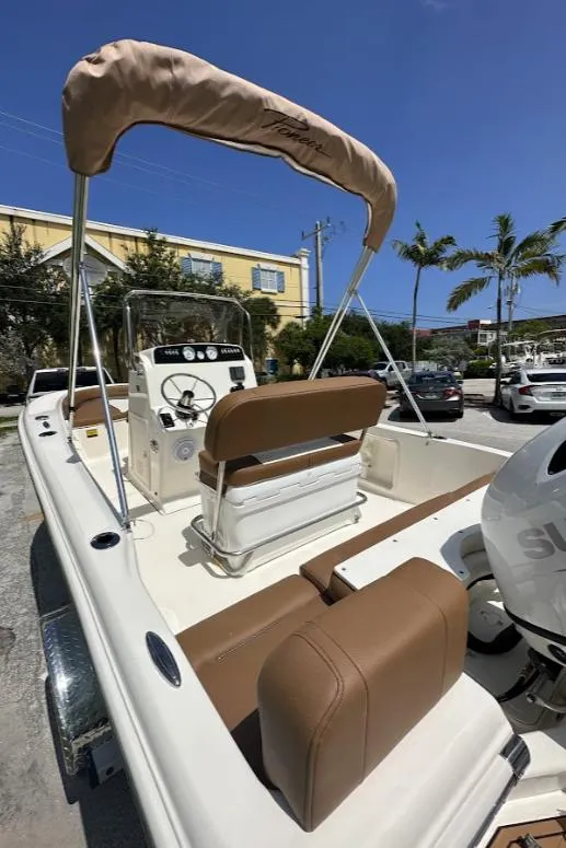 Slide: The Image of 2025 Pioneer 180 Islander boat with tan seating and canopy, parked outdoors. - 5