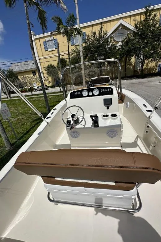Slide: The Image of 2025 Pioneer 180 Islander boat with brown seating, steering console, and gauges, outdoors. - 6