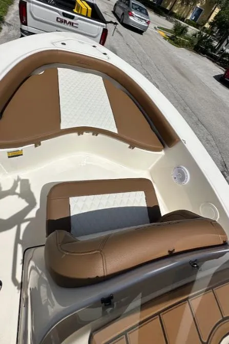 Slide: The Image of 2025 Pioneer 180 Islander boat interior with brown and white seating, parked near vehicles. - 9