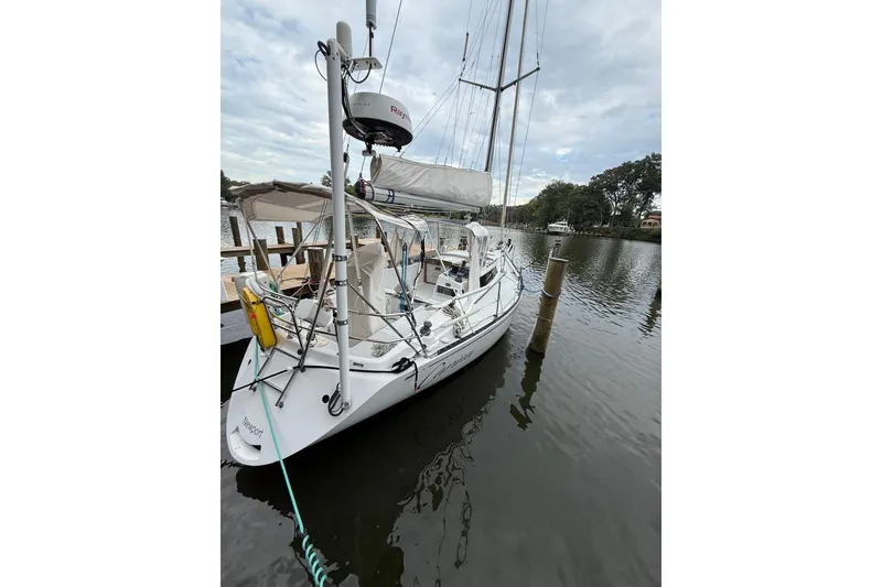 Slide: The Image of 1988 Sparkman & Stephens 36 sailboat docked on a calm river under cloudy skies. - 10