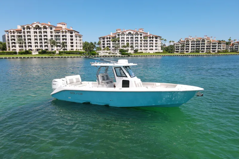 Slide: The Image of 2026 Solace 30 CS boat on clear water with luxury apartments in the background. - 2