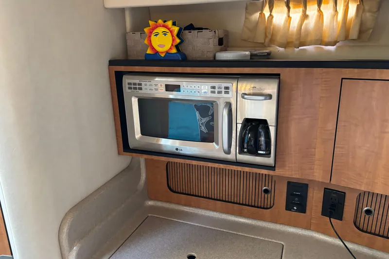 Slide: The Image of 2006 Sea Ray Sundancer 320 interior with microwave, coffee maker, and sun decoration. - 13