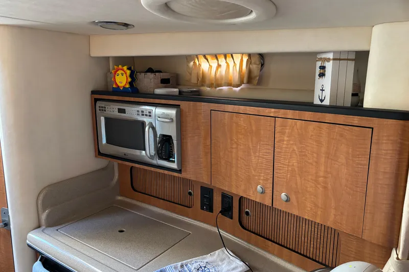 Slide: The Image of 2006 Sea Ray Sundancer 320 interior kitchen with microwave and wooden cabinets. - 16