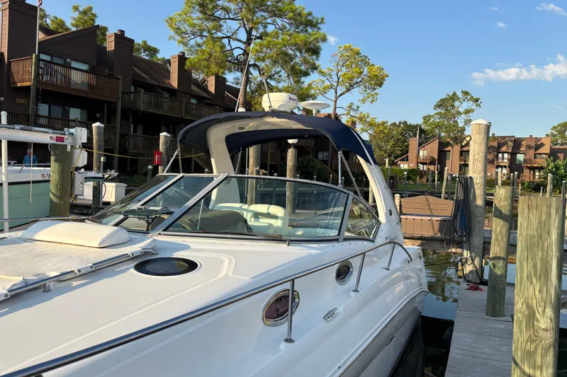 Slide: The Image of 2006 Sea Ray Sundancer 320 docked at marina, surrounded by residential buildings and trees. - 3