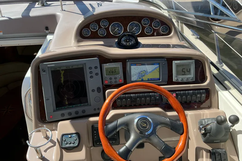 Slide: The Image of 2003 Regal Commodore 4260 boat dashboard with navigation screens and wooden steering wheel. - 37