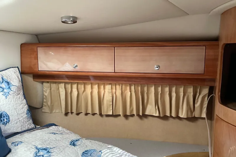 Slide: The Image of 2003 Regal Commodore 4260 cabin interior with wooden cabinets and floral bedding. - 42