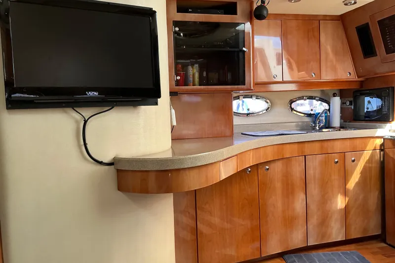 Slide: The Image of 2003 Regal Commodore 4260 yacht interior with wooden cabinets, TV, and kitchenette. - 55