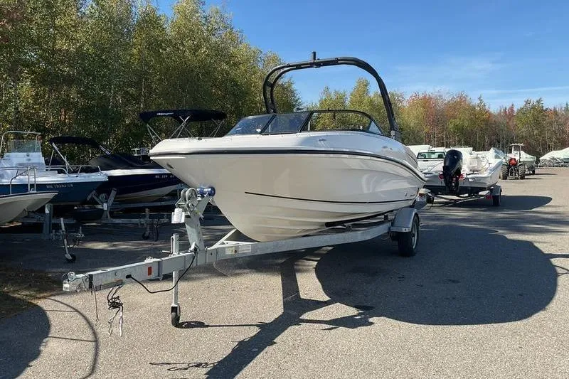 Slide: The Image of 2023 Bayliner VR5 Bowrider OB on trailer, parked outdoors with other boats. - 12