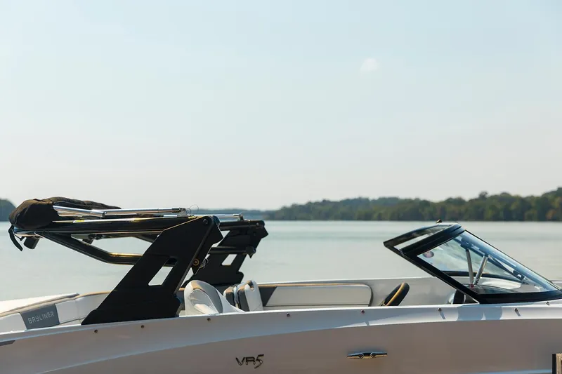 Slide: The Image of 2023 Bayliner VR5 Bowrider OB on trailer, parked outdoors with trees in background. - 5