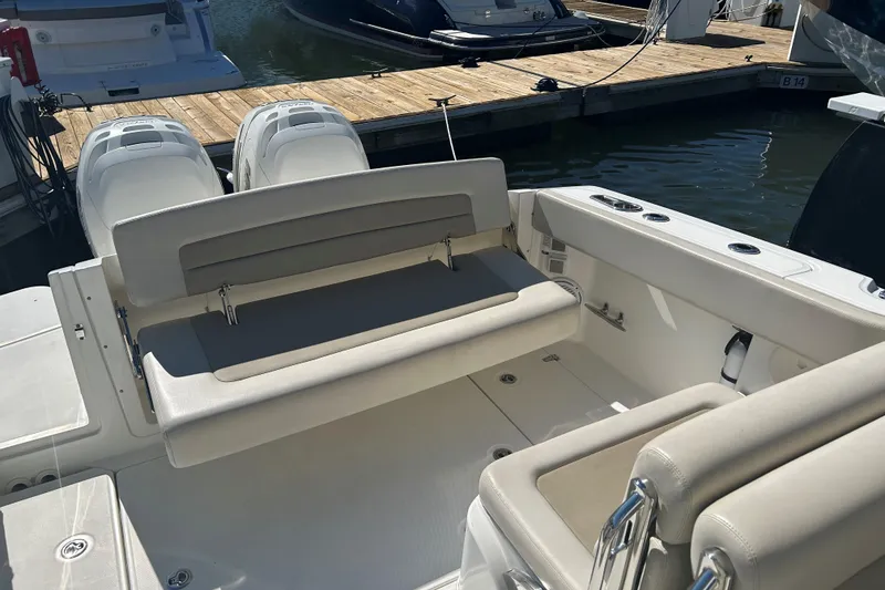 Slide: The Image of 2018 Boston Whaler 320 Vantage boat interior with seating and twin engines at dock. - 10