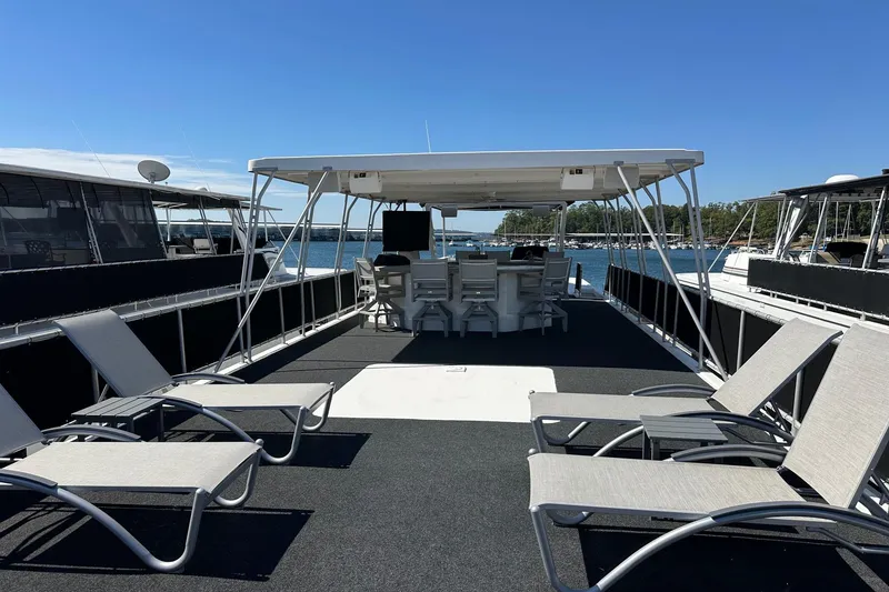 Slide: The Image of 2003 Sumerset 18x80 houseboat with sun deck, lounge chairs, and covered seating area on a sunny day. - 15