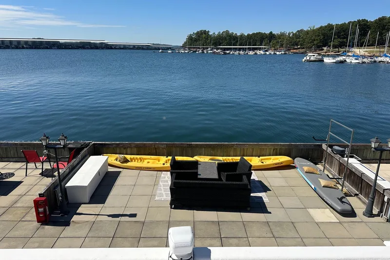 Slide: The Image of Outdoor patio with kayaks and seating overlooking a serene lake, near a marina. - 17