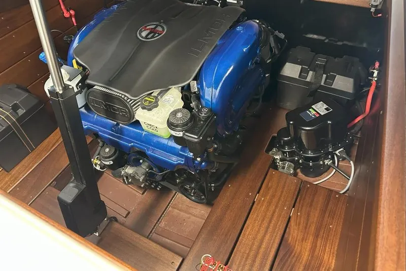 Slide: The Image of Engine compartment of 2025 StanCraft 260 Day Boat with blue engine and wooden flooring. - 18