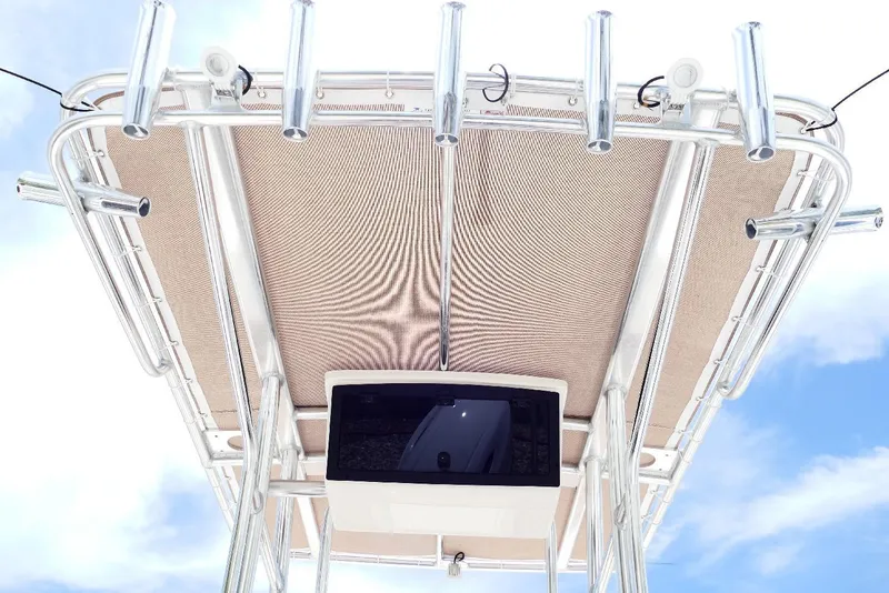 Slide: The Image of 2026 Pioneer 220 Bay Sport boat canopy with rod holders against blue sky. - 44