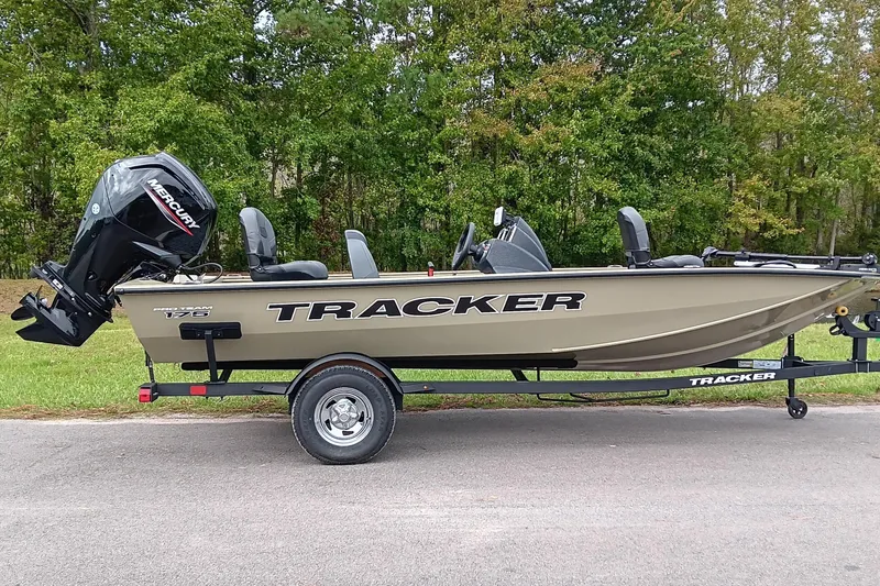 The Image of 2026 Tracker Pro Team 175 boat on trailer, parked on road with green trees in background. - 1