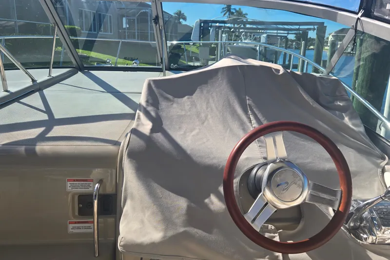 Slide: The Image of 2010 Sea Ray 330 Sundancer helm with covered dashboard and wooden steering wheel. - 15
