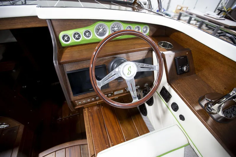 Slide: The Image of 2025 StanCraft 290 Rivelle boat dashboard with wooden steering wheel and green-accented gauges. - 19