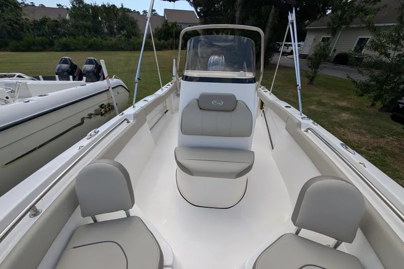 Slide: The Image of 2023 Key West 203 FS boat interior with seating and console, parked outdoors. - 13