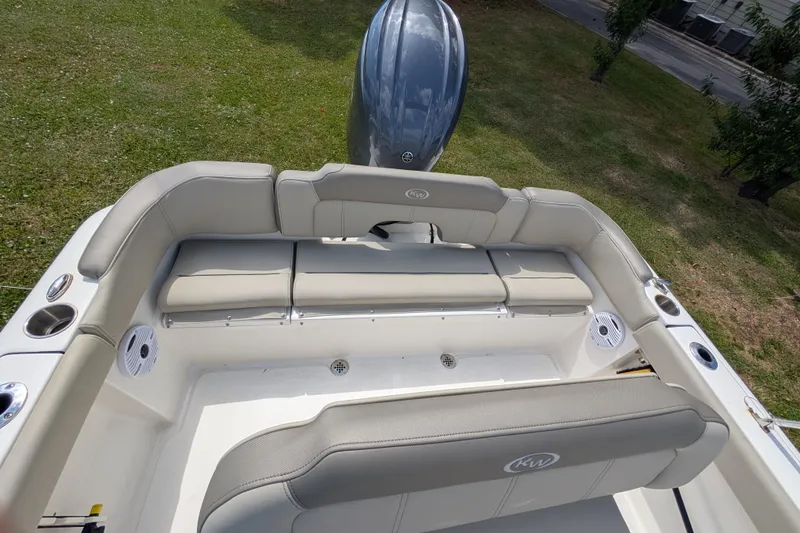 Slide: The Image of 2023 Key West 203 FS boat interior with cushioned seating and motor, on grass. - 6