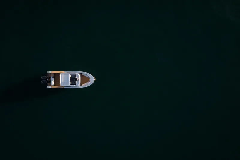 Slide: The Image of 2026 Jasper Marine Defender 22 boat illuminated on calm water at dusk. - 10