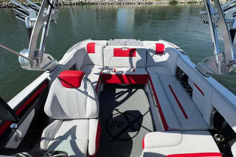 Slide: The Image of 2021 MasterCraft X22 boat interior with red and white seating, on calm water. - 11