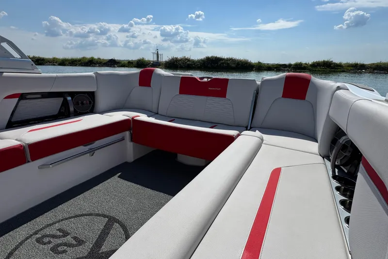 Slide: The Image of 2021 MasterCraft X22 boat interior with red and white seating, under a sunny sky. - 18