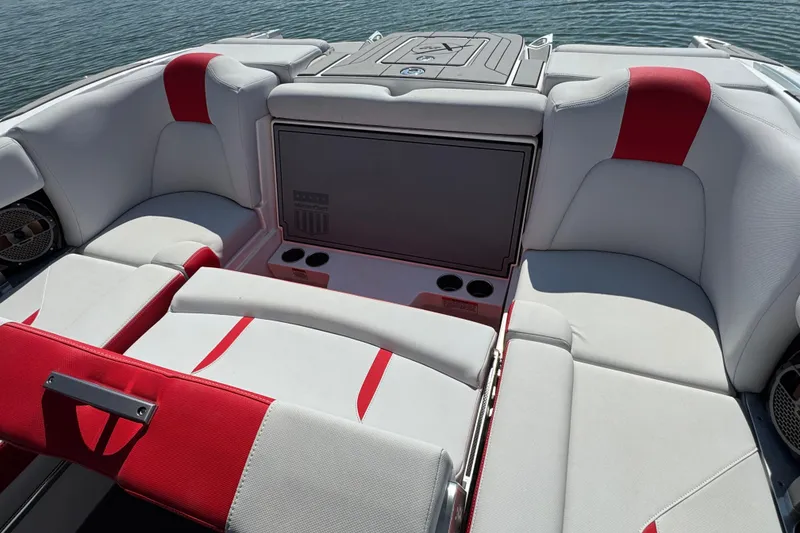 Slide: The Image of 2021 MasterCraft X22 boat interior with red and white seating, cup holders, and storage. - 19