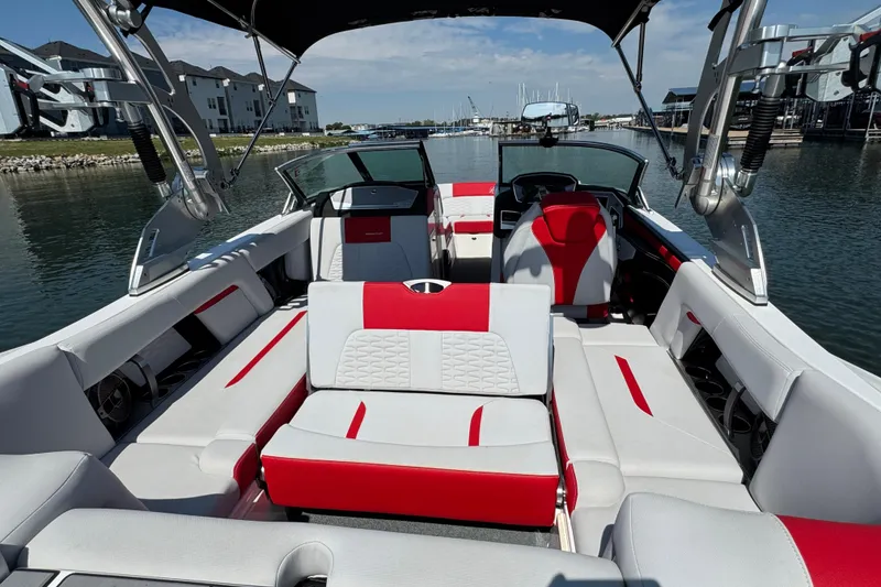 Slide: The Image of 2021 MasterCraft X22 boat interior with red and white seating, docked at marina. - 22