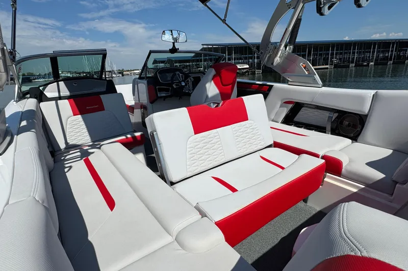 Slide: The Image of 2021 MasterCraft X22 boat interior with red and white seating, docked by the water. - 23