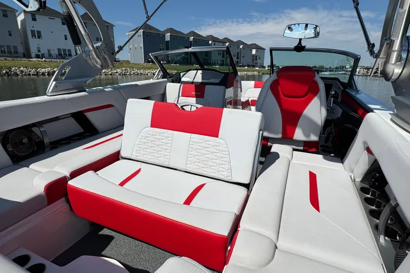 Slide: The Image of 2021 MasterCraft X22 boat interior with red and white seating, docked near waterfront homes. - 24
