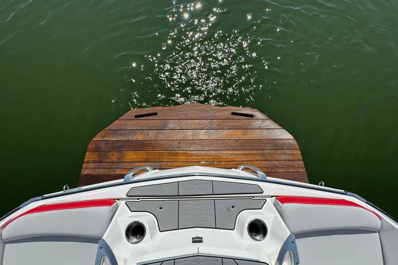 Slide: The Image of 2021 MasterCraft X22 boat stern with wooden platform on calm water. - 27