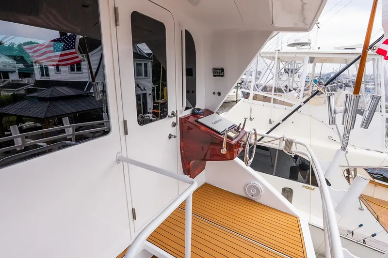 Slide: The Image of 2002 Viking 61 Enclosed Bridge yacht helm with wooden deck and marina view. - 48