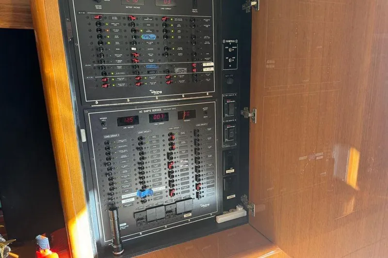 Slide: The Image of Electrical panel inside a 2002 Viking 61 Enclosed Bridge yacht, featuring various switches and controls. - 74