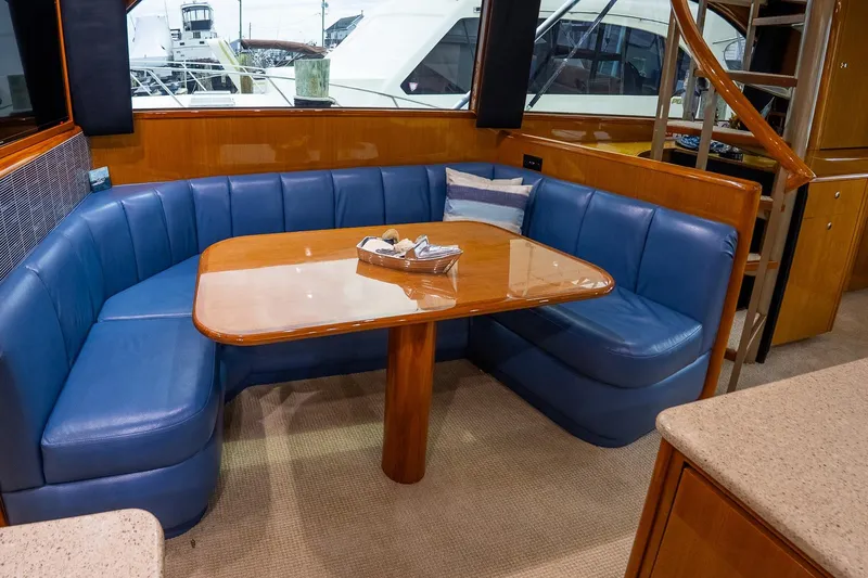Slide: The Image of Luxurious interior of 2002 Viking 61 Enclosed Bridge yacht with blue seating and wooden table. - 89