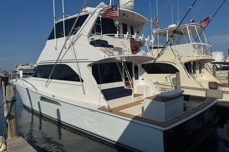 Slide: The Image of 2002 Viking 61 Enclosed Bridge yacht docked at marina, featuring sleek design and American flags. - 9